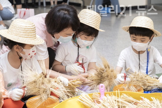 구청 화단에서 키운 보리를 아이들과 수확 탈곡하는 ‘도시농부, 아이농부 보리 수확 체험’ 행사를 하고 있다. [제공=금정구청]